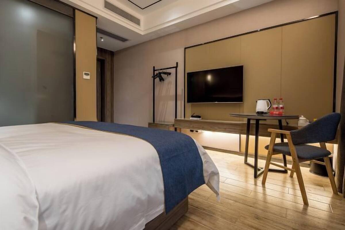 A hotel room with a bed, a desk with a chair, a flat-screen TV, and a coffee maker.