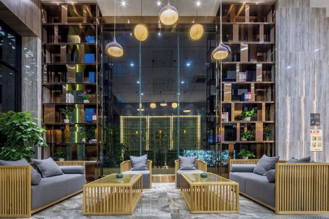 A modern lobby with a central seating area, bookshelves, and a glass partition.