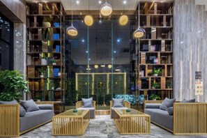 A modern lobby with a central seating area, bookshelves, and a glass partition.