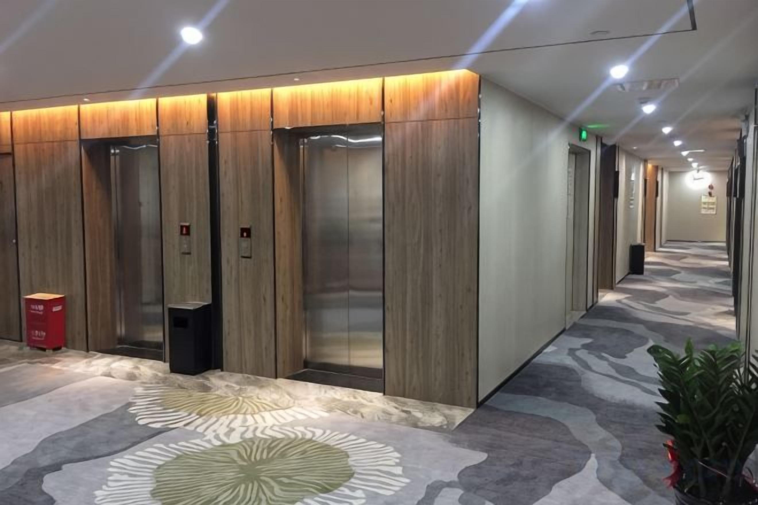 A hotel corridor with elevators and a patterned carpet.