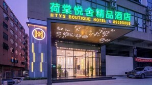 Un hotel con fachada moderna, amplios ventanales de vidrio y un letrero de neón que indica que es un hotel boutique.