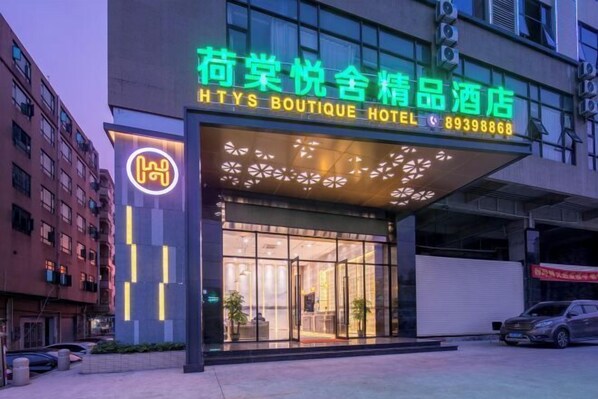 A hotel with a modern facade, large glass windows, and a neon sign indicating it is a boutique hotel.