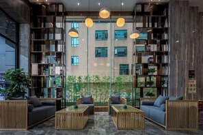 A modern interior with a seating area, bookshelves, and a view of a building. - HTYS Boutique Hotel (Dongguan)