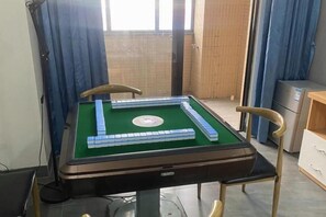A pool table with a green felt surface and blue stripes, surrounded by chairs.