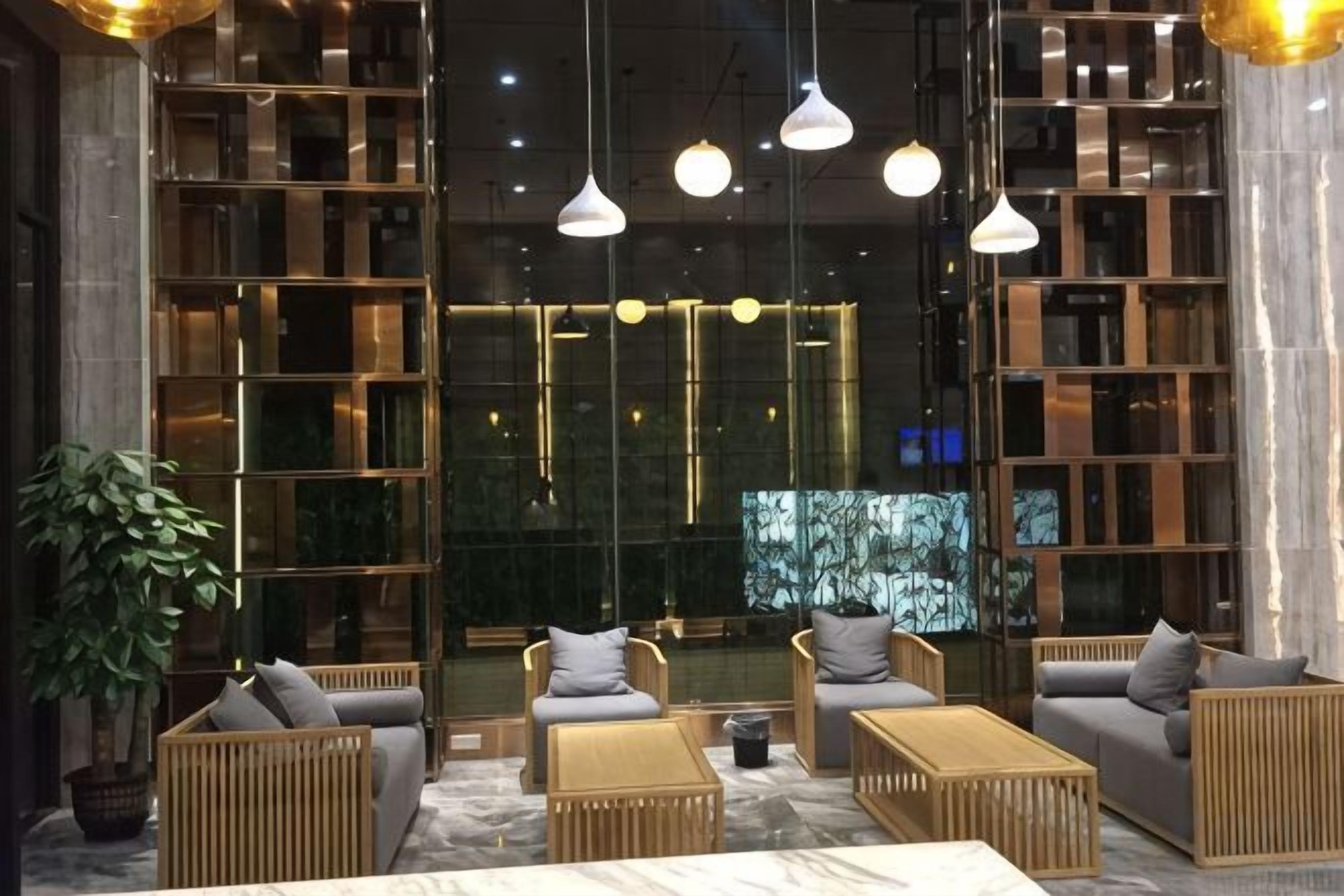 A modern lobby with seating arrangements, a large mirror, and hanging pendant lights.