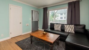 A living room with a black leather sofa, a wooden coffee table, and a patterned rug. - Central Tosa home near downtown, state fair, froedtert (Wauwatosa)