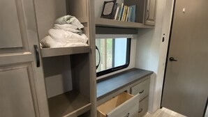 Una habitación pequeña con una litera, un escritorio con computadora y una puerta.