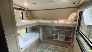 Interior compacto de autocaravana con dos literas, un espacio pequeño para sentarse y una ventana.