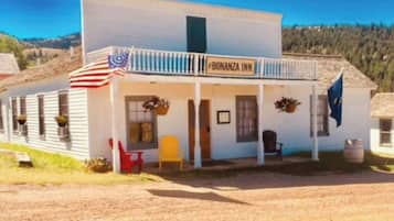Experience the charm of the Bonanza Inn, a two-story building with a balcony and seating area, nestled in a serene rural setting.