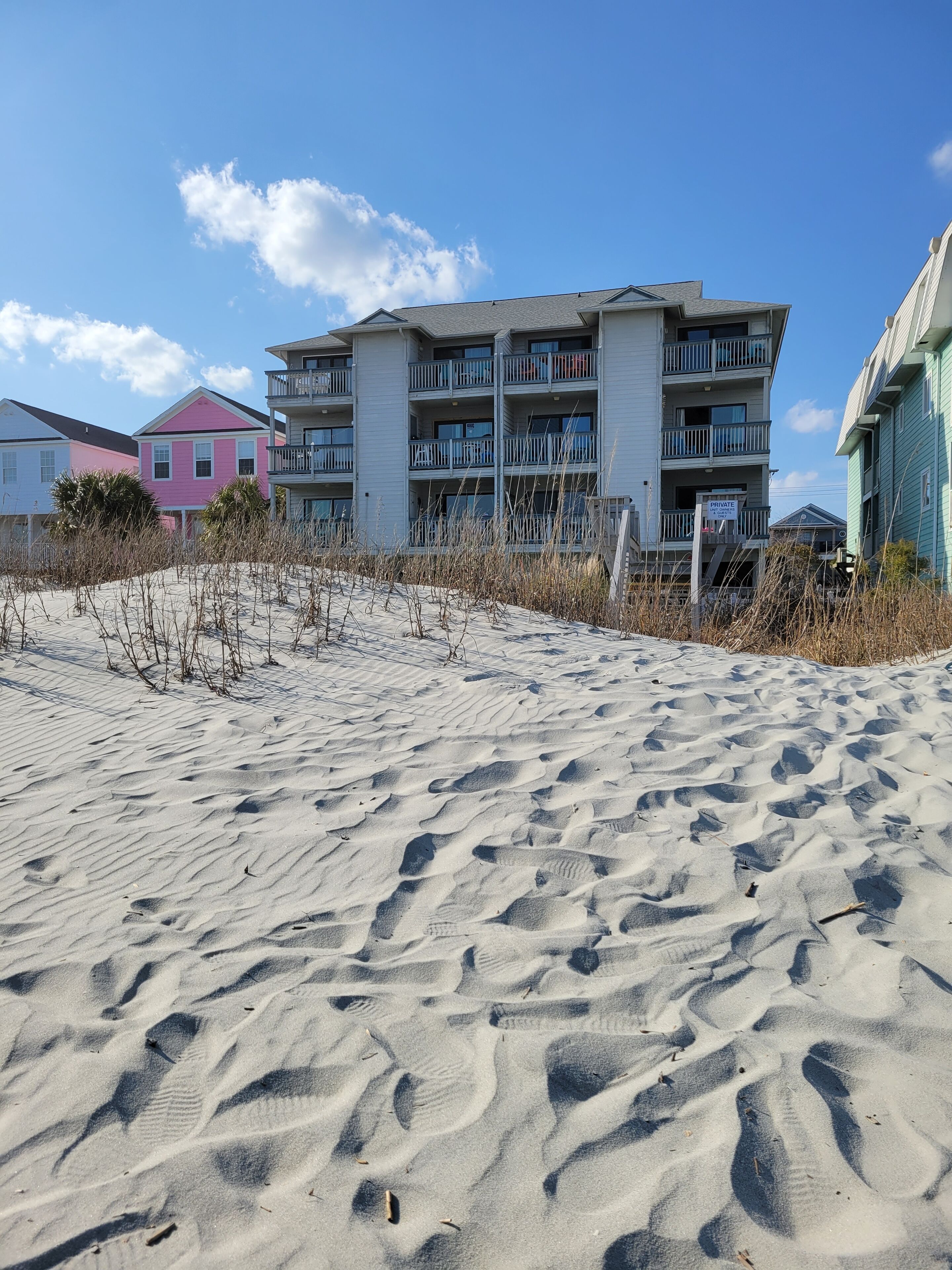 A beachfront building with multiple balconies and a private sign.