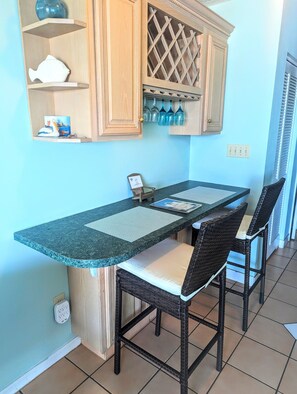 A kitchen with a dark granite countertop, wooden cabinets, and a built-in wine rack. - Oceanfront Getaway, Directly on the Beach with Amazing Views (Surfside Beach)