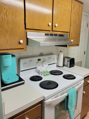 Kitchen equipped with a stove, oven, toaster, and kettle.