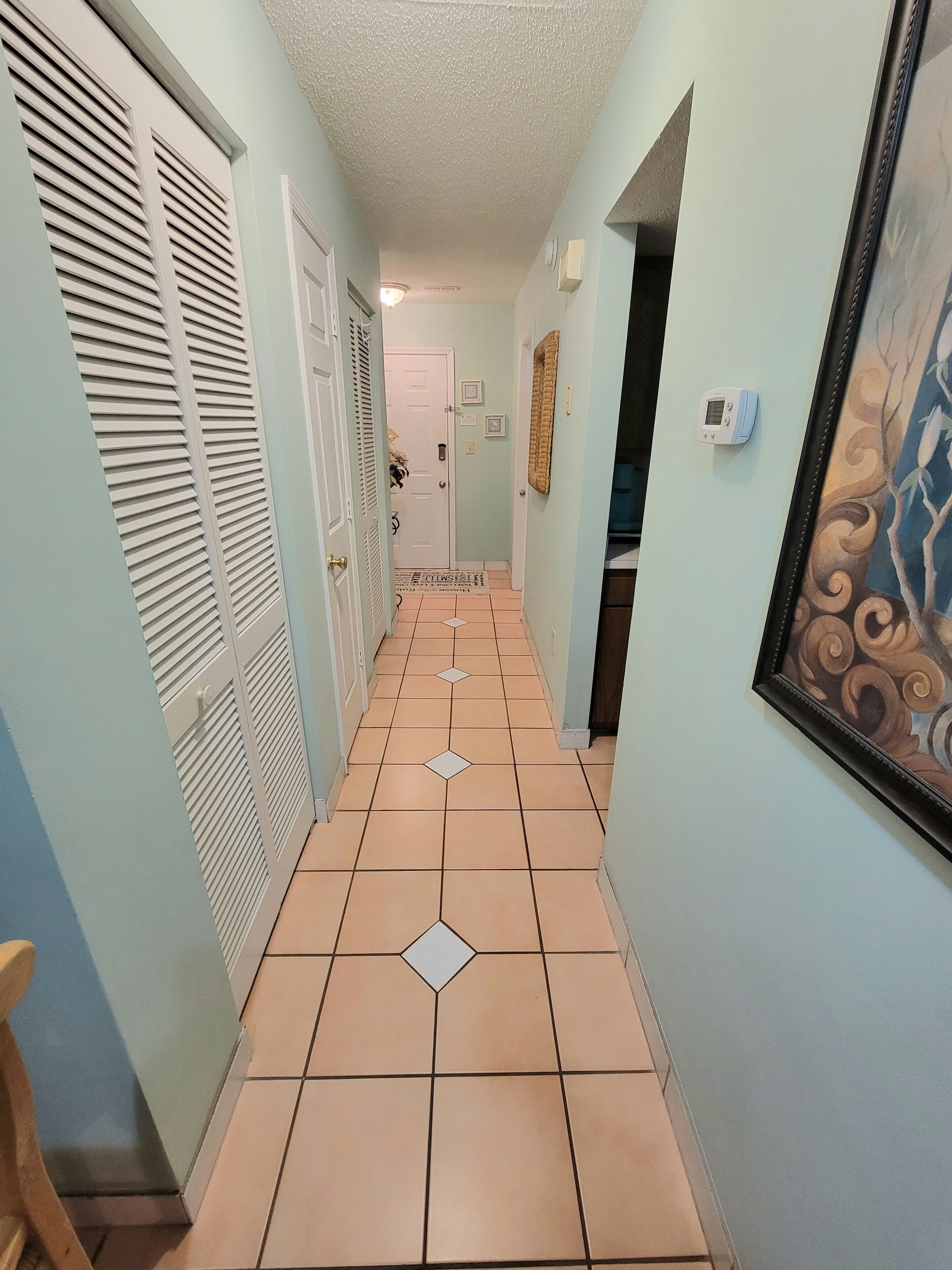 Un pasillo con paredes azul claro, puertas blancas y piso de baldosas con diseños de diamantes.