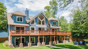 A two-story house with a covered patio, stone pillars, and a fenced backyard. - Cozy Dog Friendly, Private Dock & Fire Pit (Oakland)