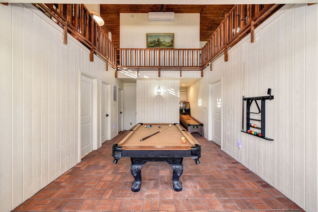 A pool table in a hallway with white walls and a wooden ceiling.