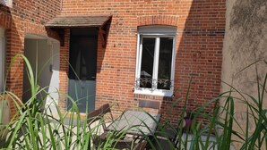 Ein Backsteinhaus mit Fenster, Tür und einer kleinen überdachten Fläche.