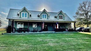 A two-story house with a stone foundation, a front porch, and a flag.