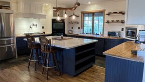 A modern kitchen with a central island, bar stools, and a large window.