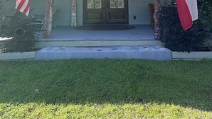 A house with a welcoming front door, two flags, and a well-maintained lawn.