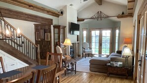 A spacious living area with a wooden staircase, a comfortable sofa, and a dining table with chairs.
