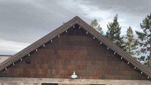 Maalaishenkinen mökki, jossa on puinen ulkoverhous, etuovi ja kaksi ikkunaa.
