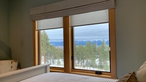 Makuuhuone, jossa on suuri ikkuna, sänky ja näkymä lumiseen maisemaan.