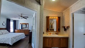 Un dormitorio con cama, cómoda, espejo y ventilador de techo.