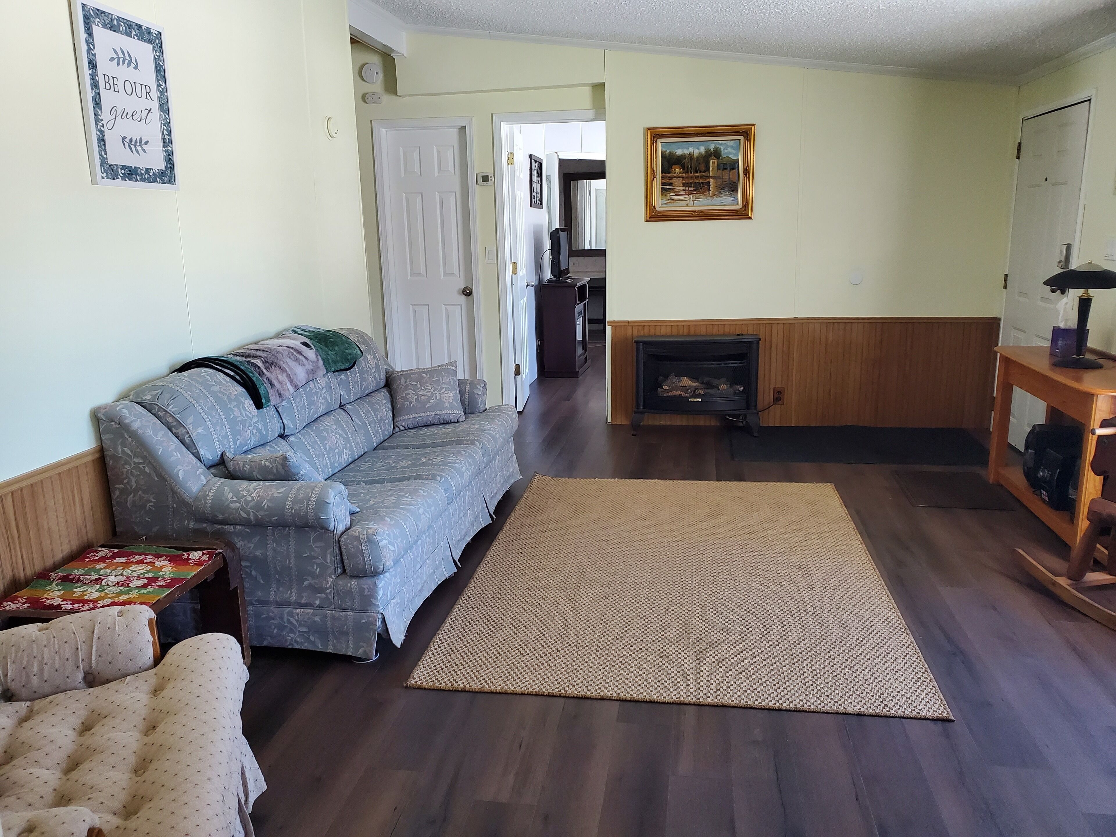 Ein Wohnzimmer mit einer Couch, einem Teppich, einem Kamin und einem Gemälde an der Wand.