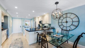 Una cocina moderna con armarios blancos, una isla de vidrio y un gran reloj de pared.