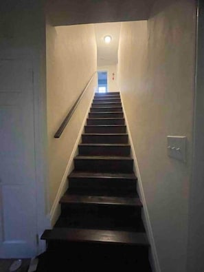 A narrow staircase with a handrail, leading to a door at the top.