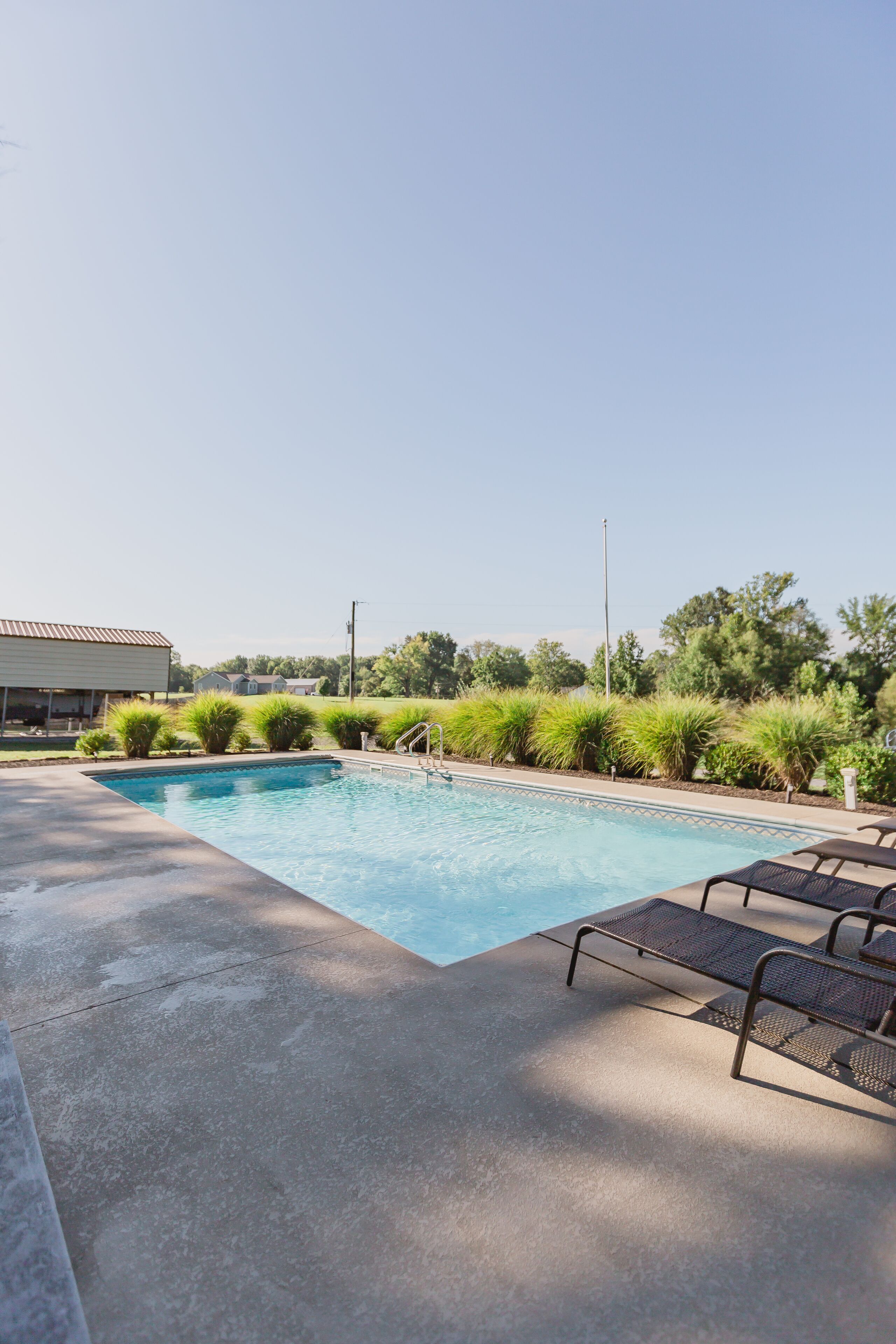 A swimming pool with lounge chairs and a covered area.