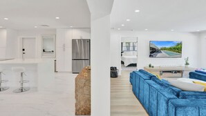 Una cocina moderna con una isla central, electrodomésticos de acero inoxidable y una zona de comedor con taburetes de bar.