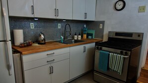 A kitchen with white cabinets, a stainless steel stove, and a wooden countertop. - Lovely 1 Bedroom Garden flat in Victorian Building (San Francisco)