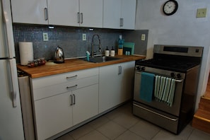 A kitchen with white cabinets, a stainless steel stove, and a wooden countertop.