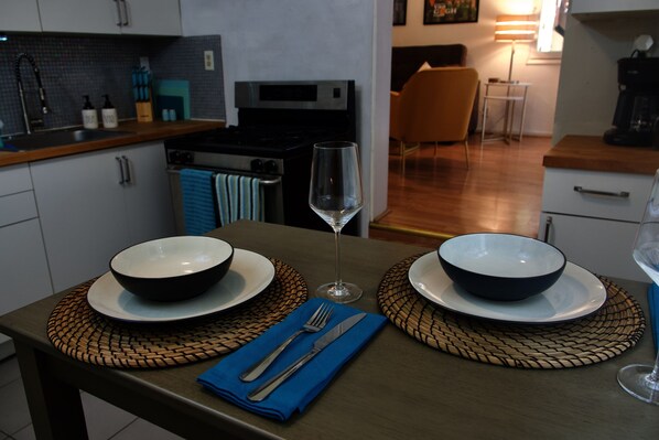 A modern kitchen with two bowls on a table, a wine glass, and a blue napkin.