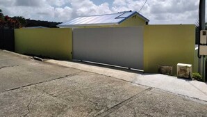 Un bâtiment doté d’un grand portail de garage, d’un toit en pente et surplombant un ciel dégagé parsemé de nuages.