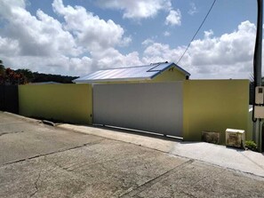 Un edificio con una puerta de garaje grande, techo inclinado y cielo despejado con nubes.