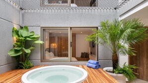 Ein Wellnessbereich mit Whirlpool, Holzterrasse und Pflanzen in Töpfen.