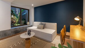 A modern living room with a white sofa, a round coffee table, and a dining area with a wooden table and chairs.