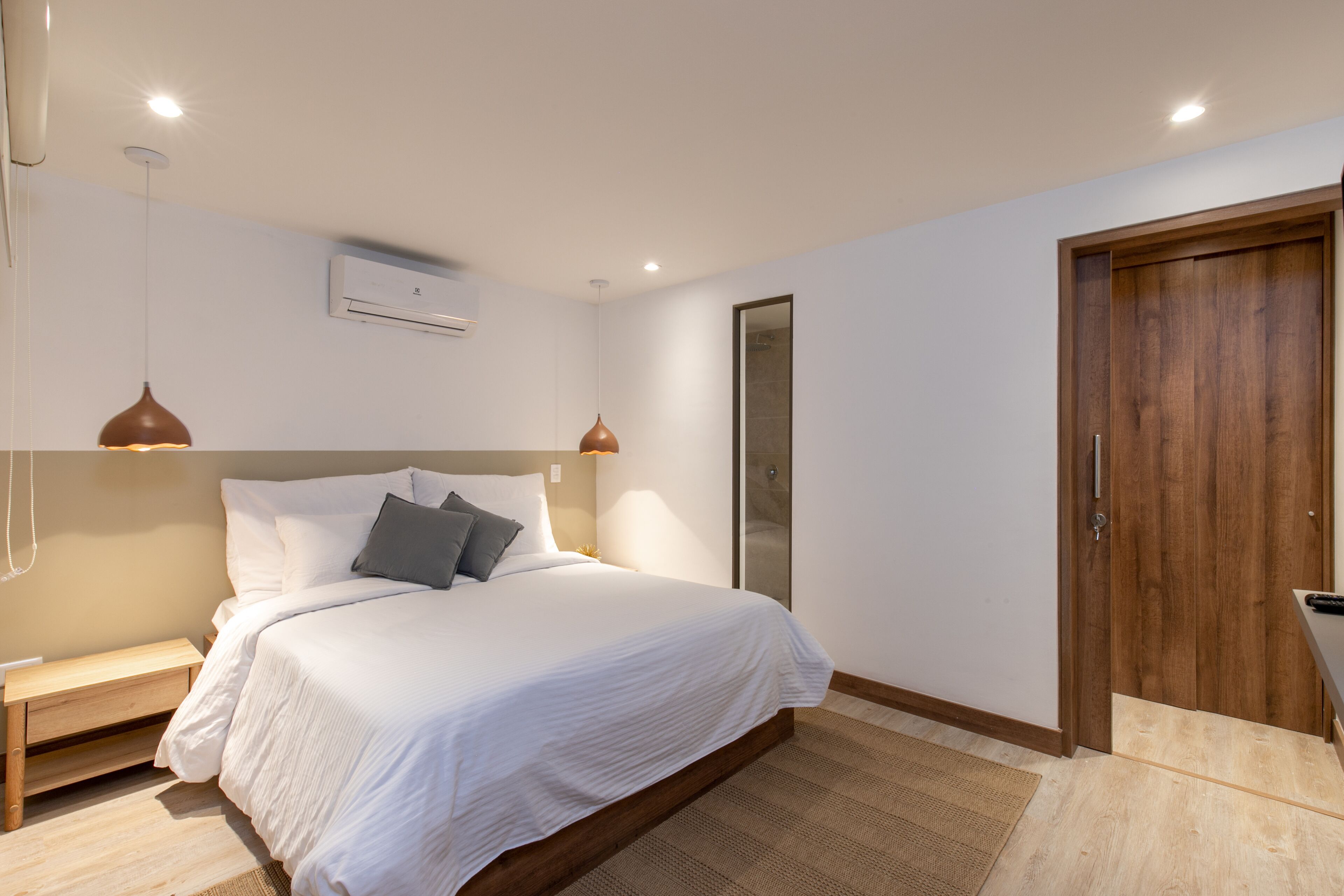 A modern bedroom with a large bed, bedside tables, and a wooden wardrobe.