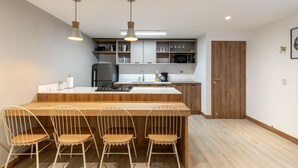 A modern kitchen with a wooden island, white chairs, and built-in appliances.
