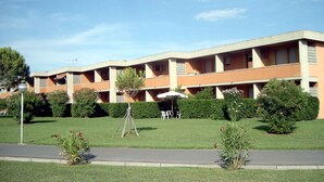Ein mehrgeschossiges Hotel mit flachem Dach, Balkonen und einem gepflegten Rasen.