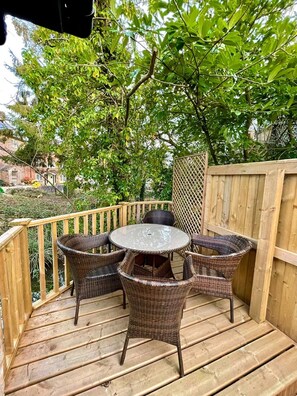 A wooden deck with wicker furniture and a glass table. - Charming 2-bed Lodge in Dorchester (Dorchester)