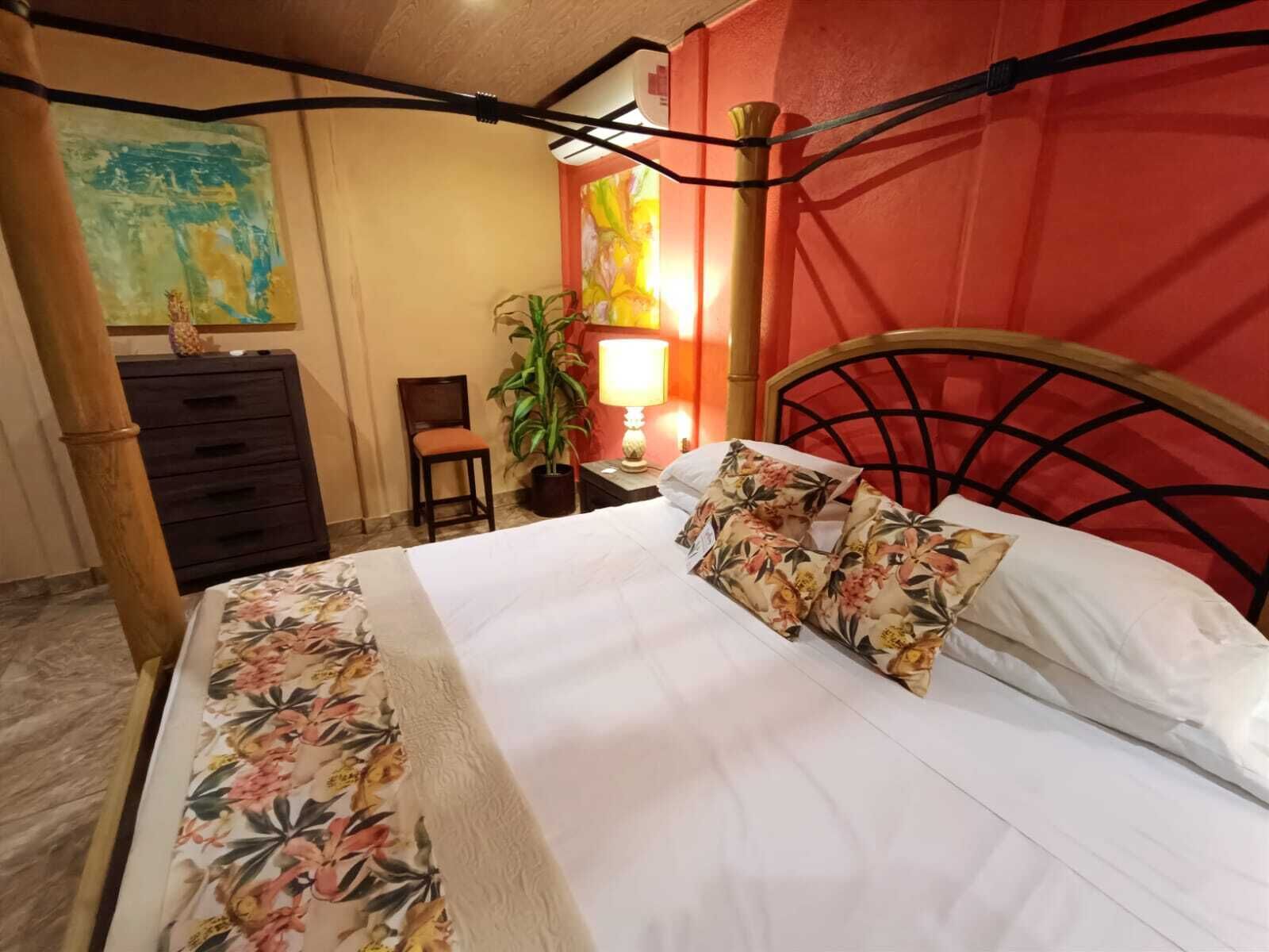 A hotel room with a bed, a nightstand, a chair, a lamp, and a painting on the wall.