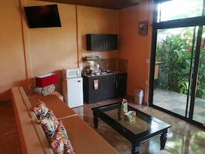 Relax in this cozy space with a sofa, TV, and kitchenette, offering a convenient escape with a sliding door to an outdoor area.