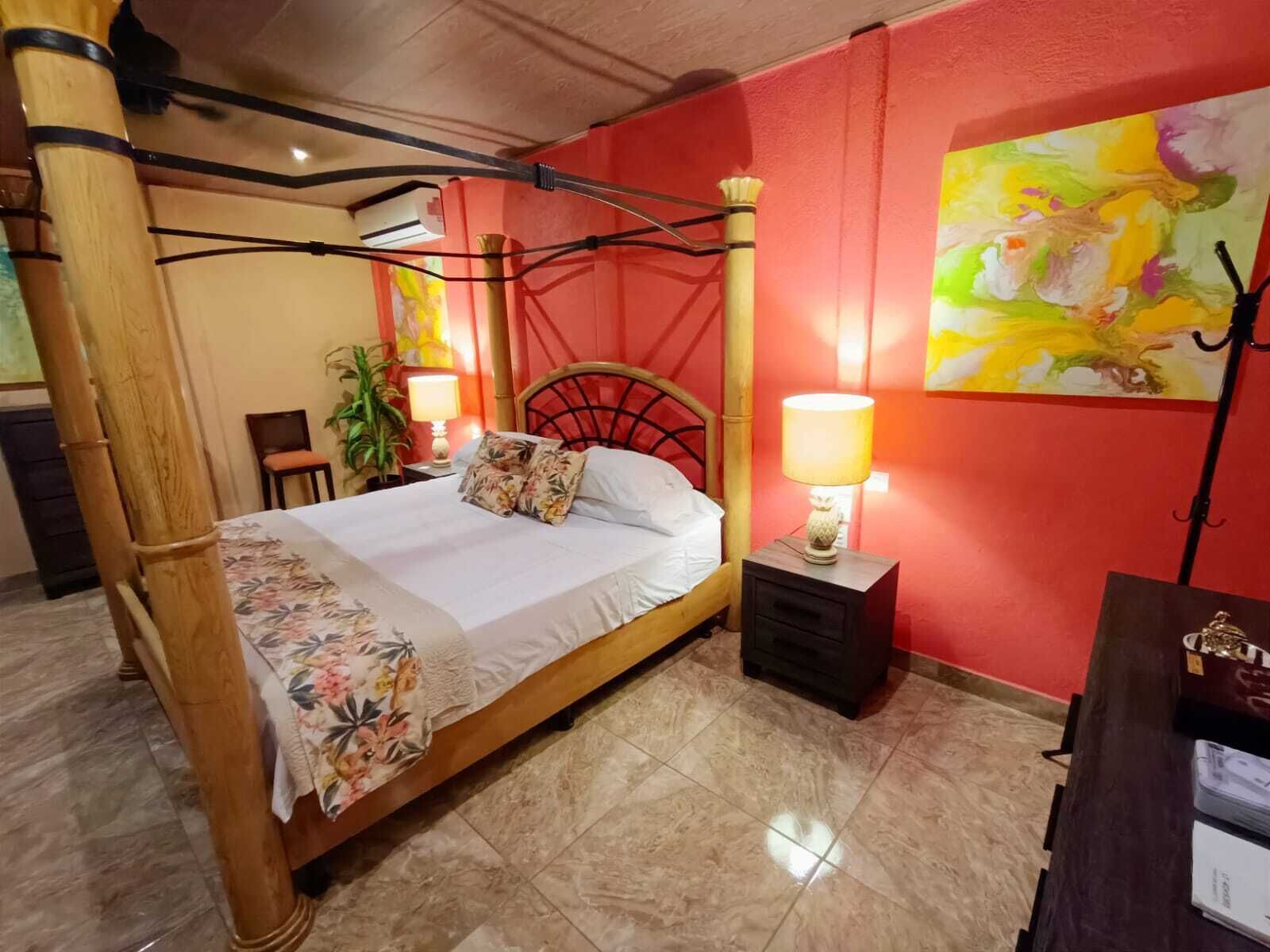 Un letto a baldacchino con copriletto floreale, un comodino con una lampada e un quadro appeso al muro.