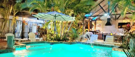 A pool area with lounge chairs and a bar.