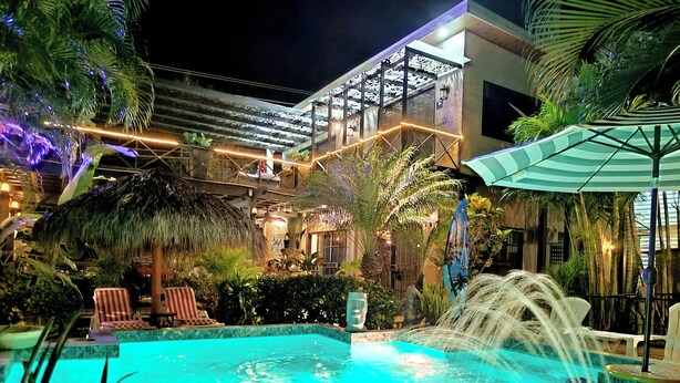 A pool area with a water feature, lounge chairs, and tropical plants.