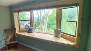 Una habitación con un amplio asiento junto a la ventana con vistas a una terraza y árboles.