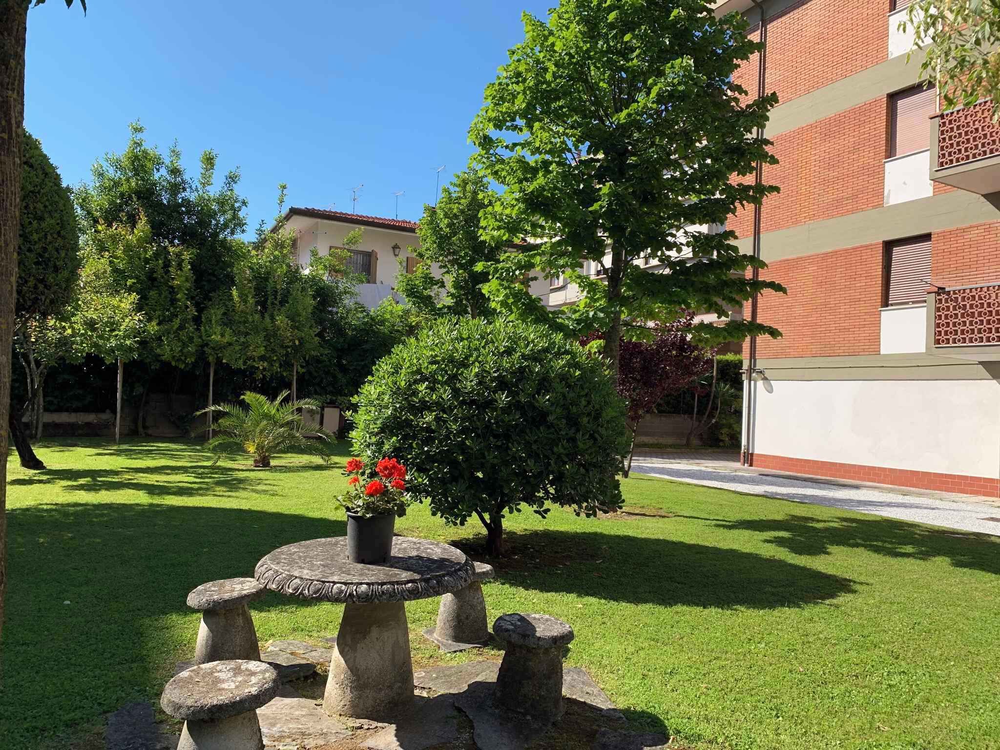 A courtyard with a stone table, potted plants, and a brick building in the background.